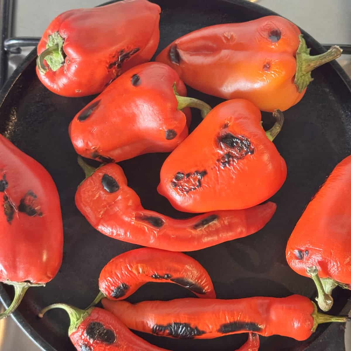 Roasting red peppers on a blue steel pan.