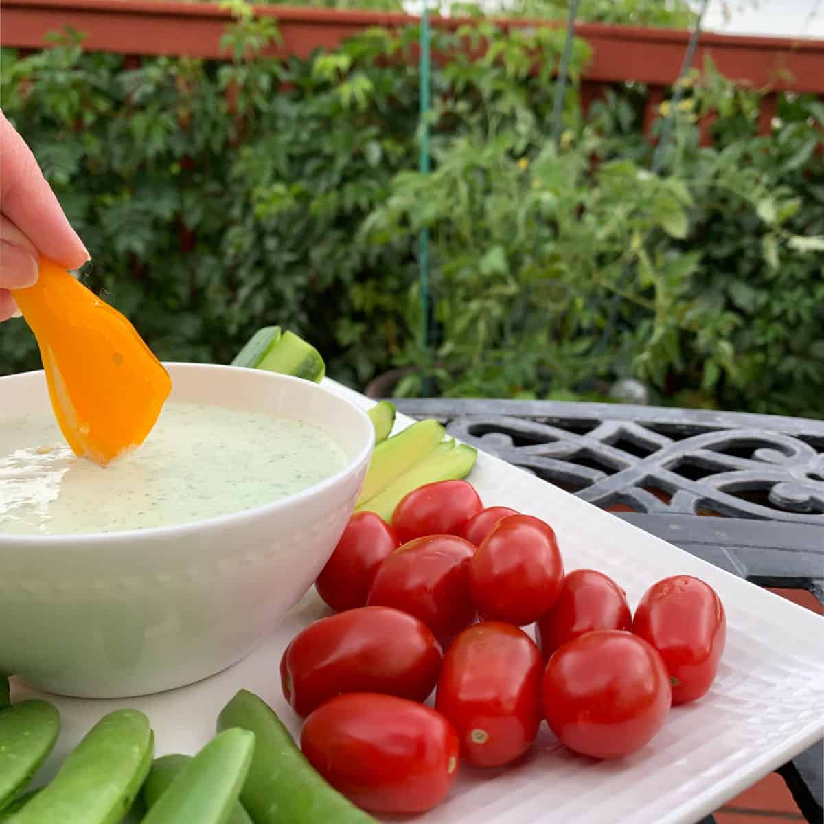 The dip in a bowl scooping with a mini yellow bell pepper.
