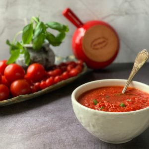 Sugo in a bowl and tomatoes in the background.