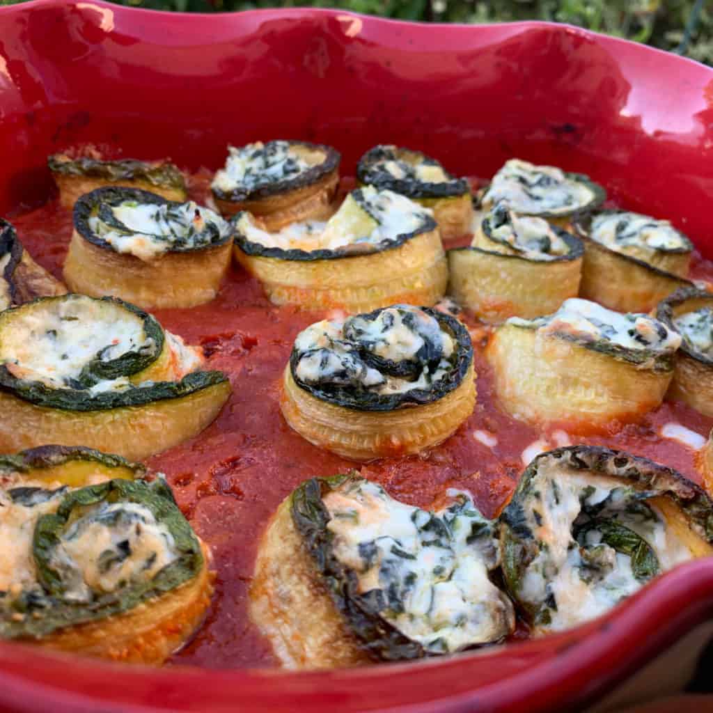 Zucchini rollatini in a red dish.