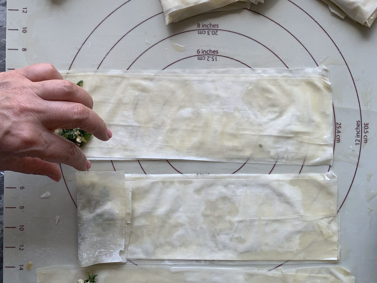 Folding phyllo dough over to cover the filling.