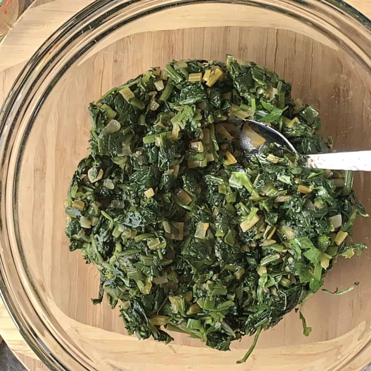 Spinach, feta filling for spanakopita in a glass bowl.