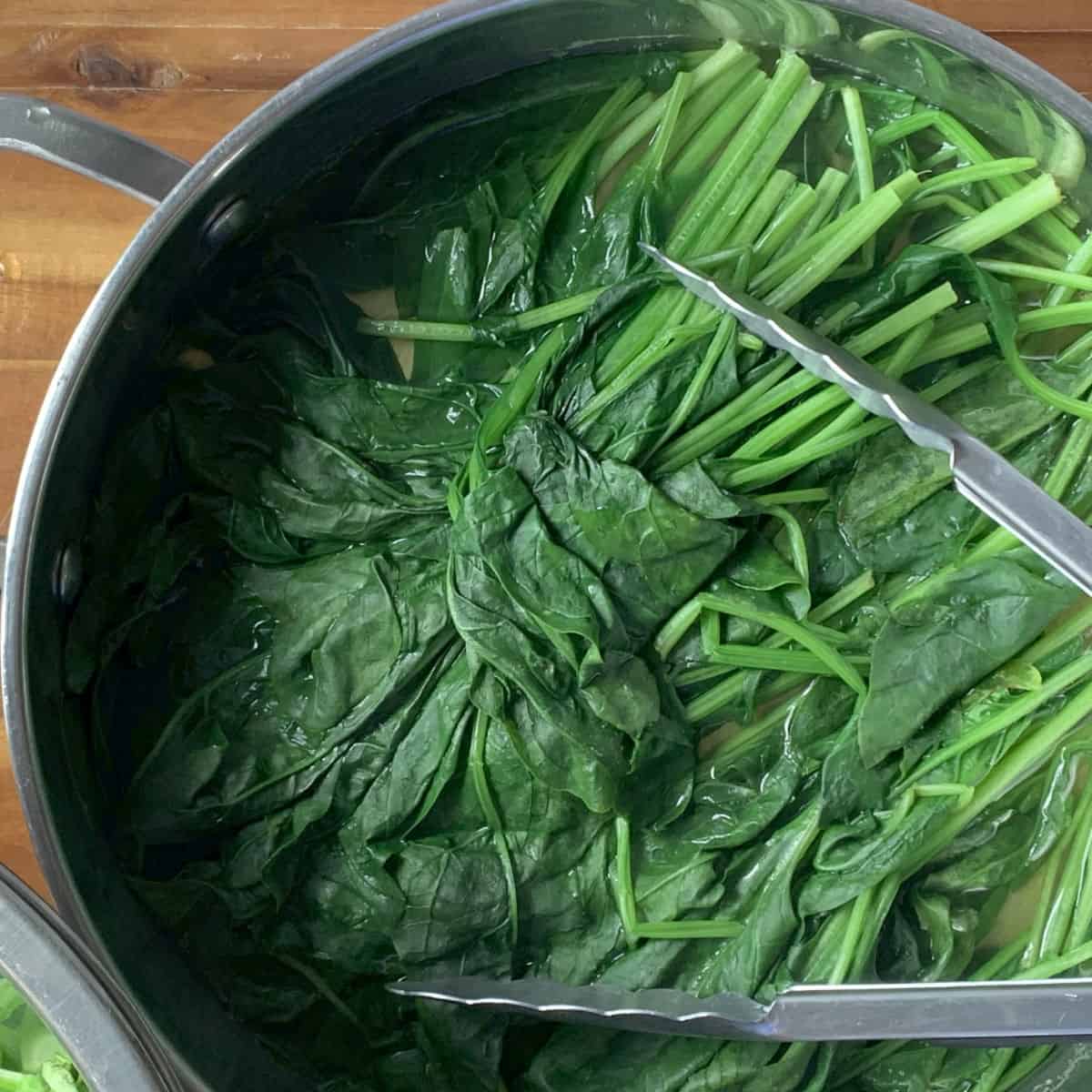 Blanching spinach in a cooking pan.