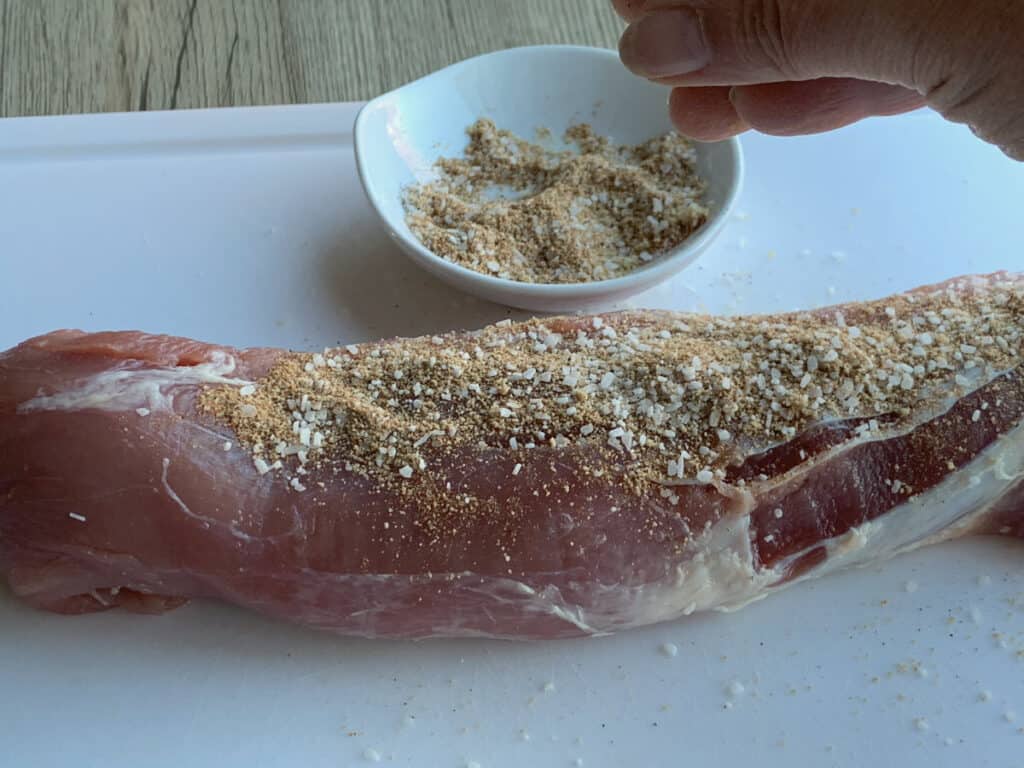 Applying the dry rub on a pork tenderloin.
