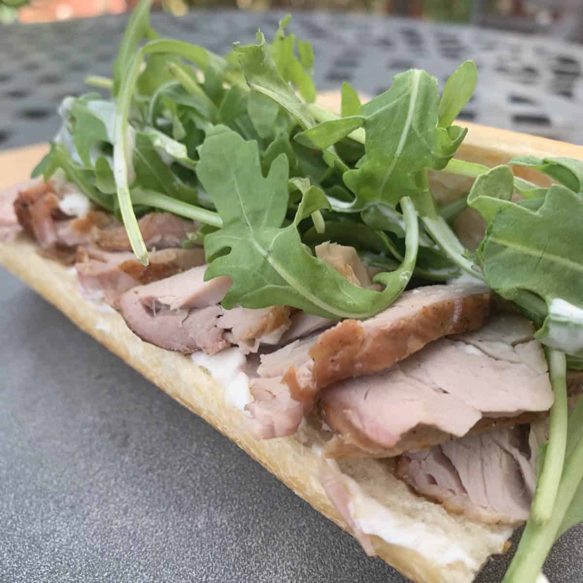 Smoked tenderloin sandwich with mayo and arugula.