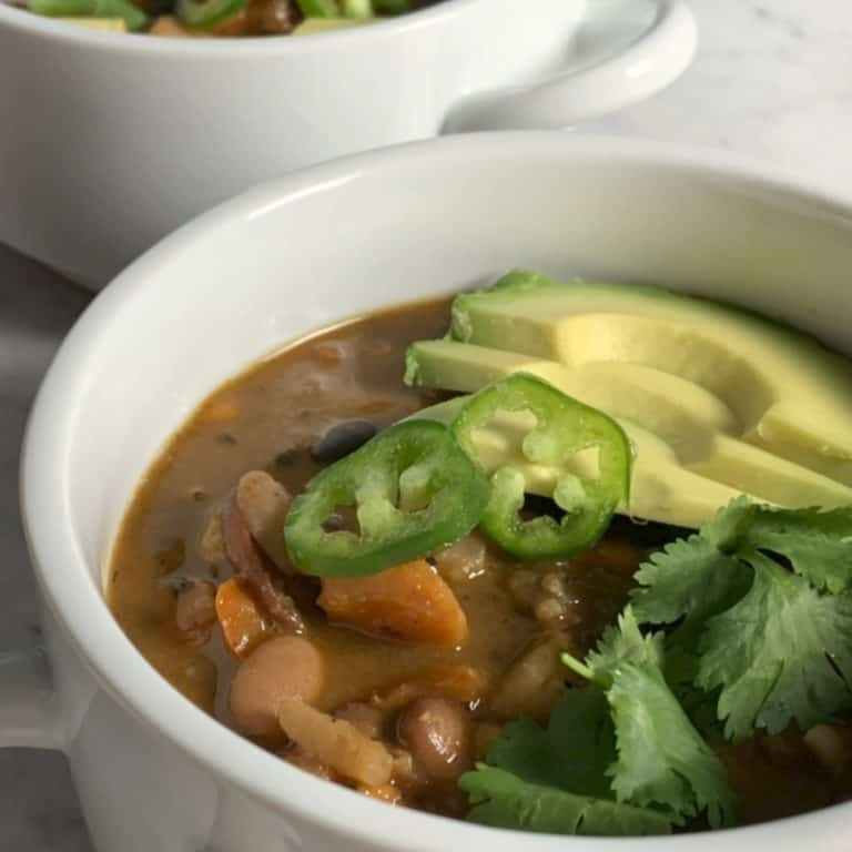 Three bean chili garnished with cilantro, avocado and jalapeños.