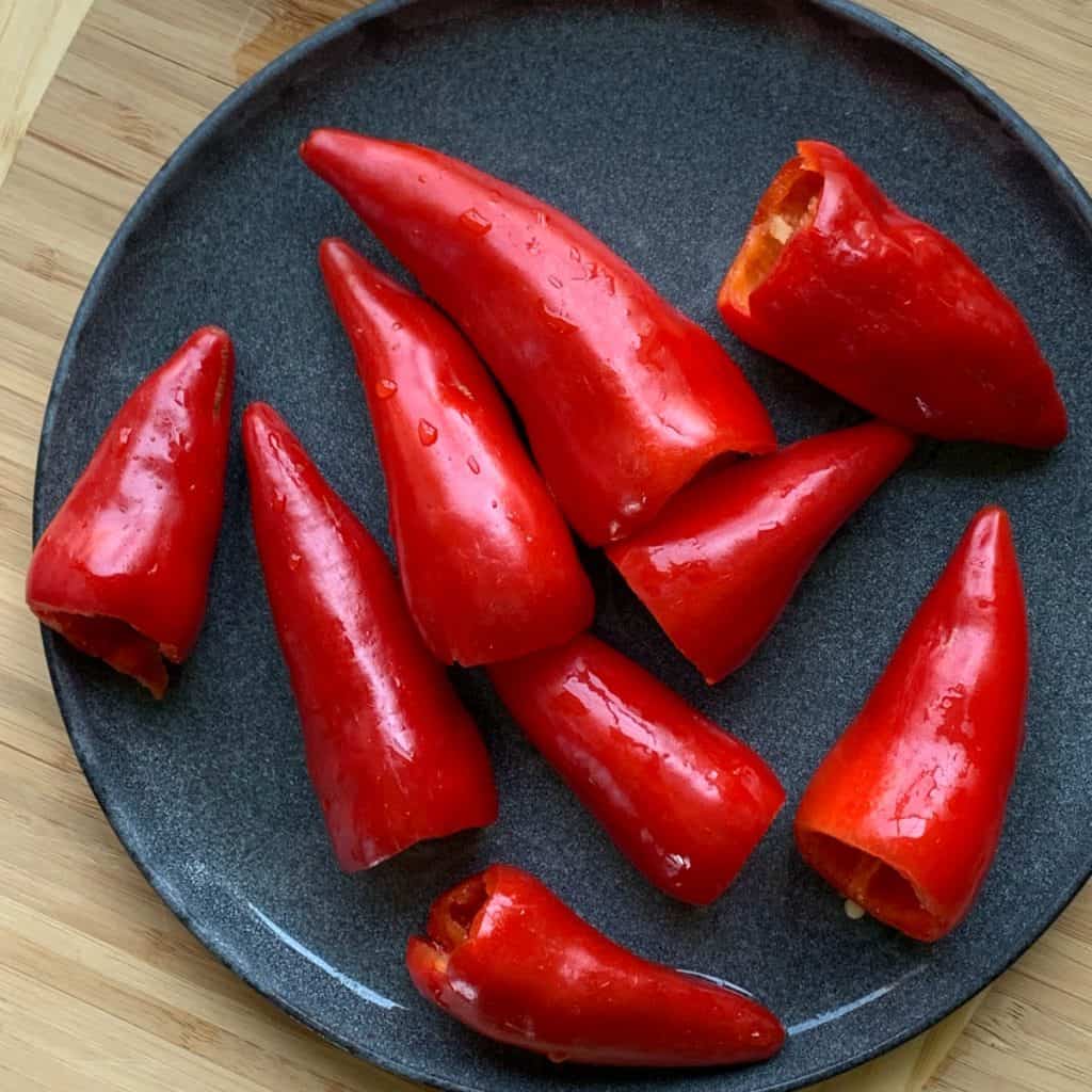 Washed, cleaned fresno peppers on a black plate.