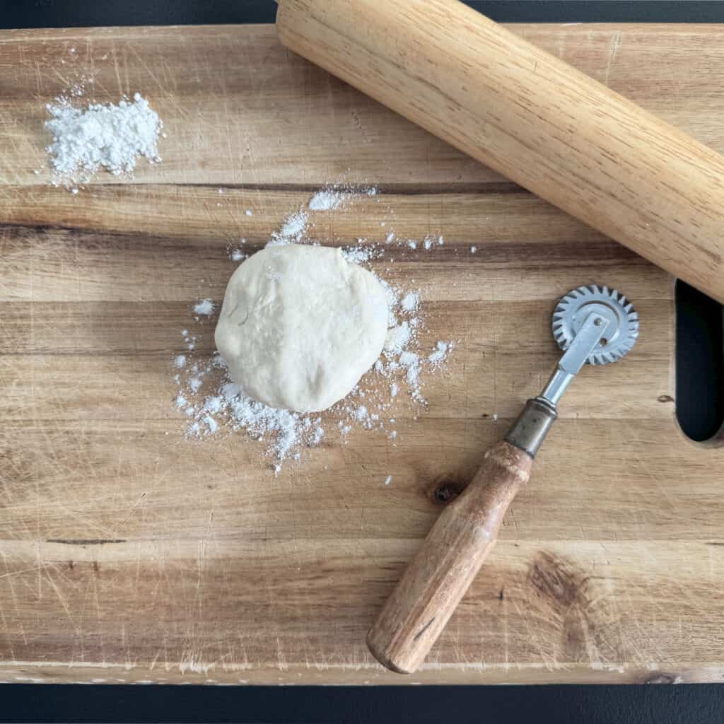 Dough with rolling pin and ravioli cutter.
