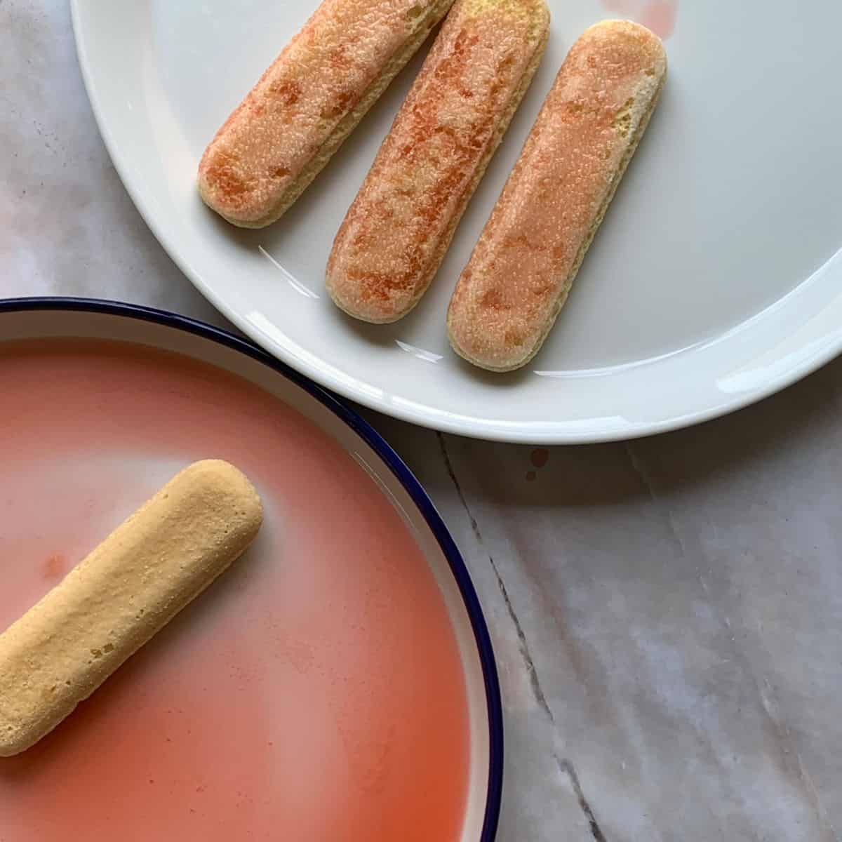 Dunking the ladyfingers in the strawberry syrup.