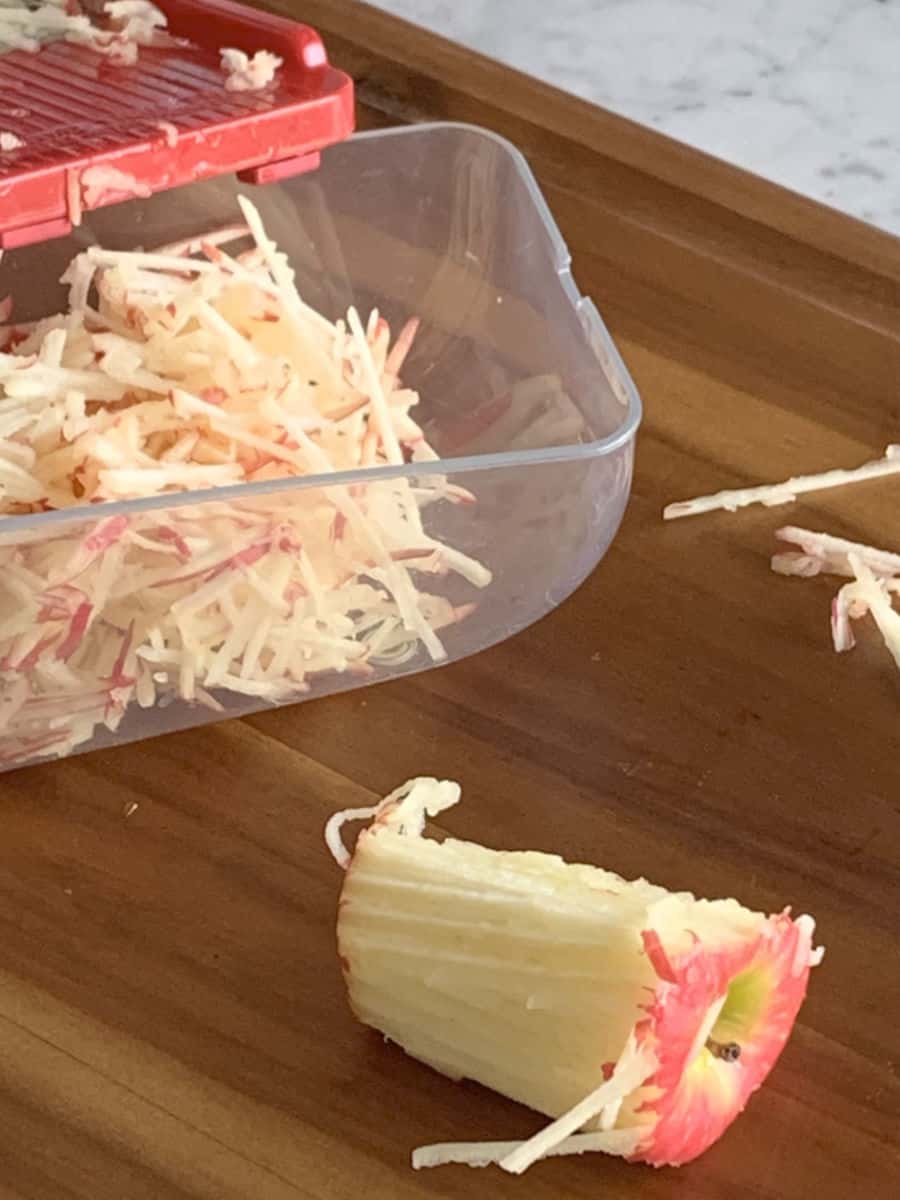 Shredded apple in a container and core of an apple.