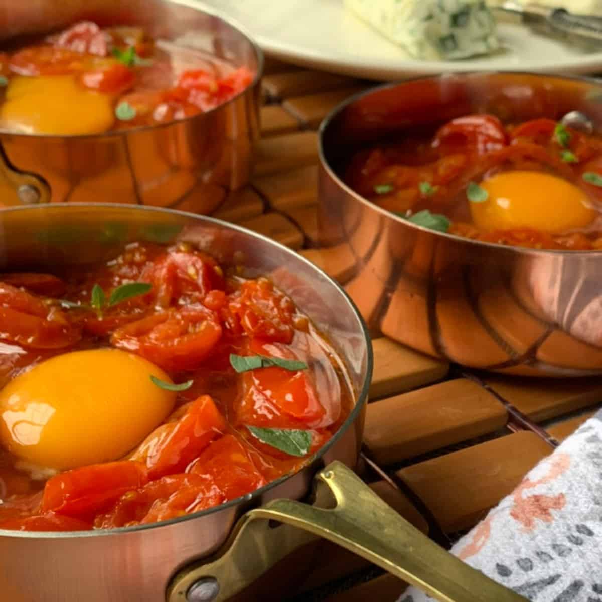 The eggs and tomato confit in a small copper pan ready to be baked.