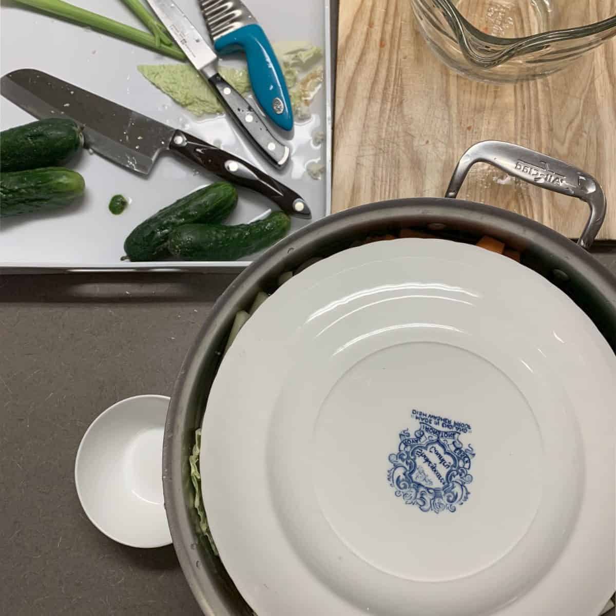 Placing a smaller plate to hold down the vegetables.