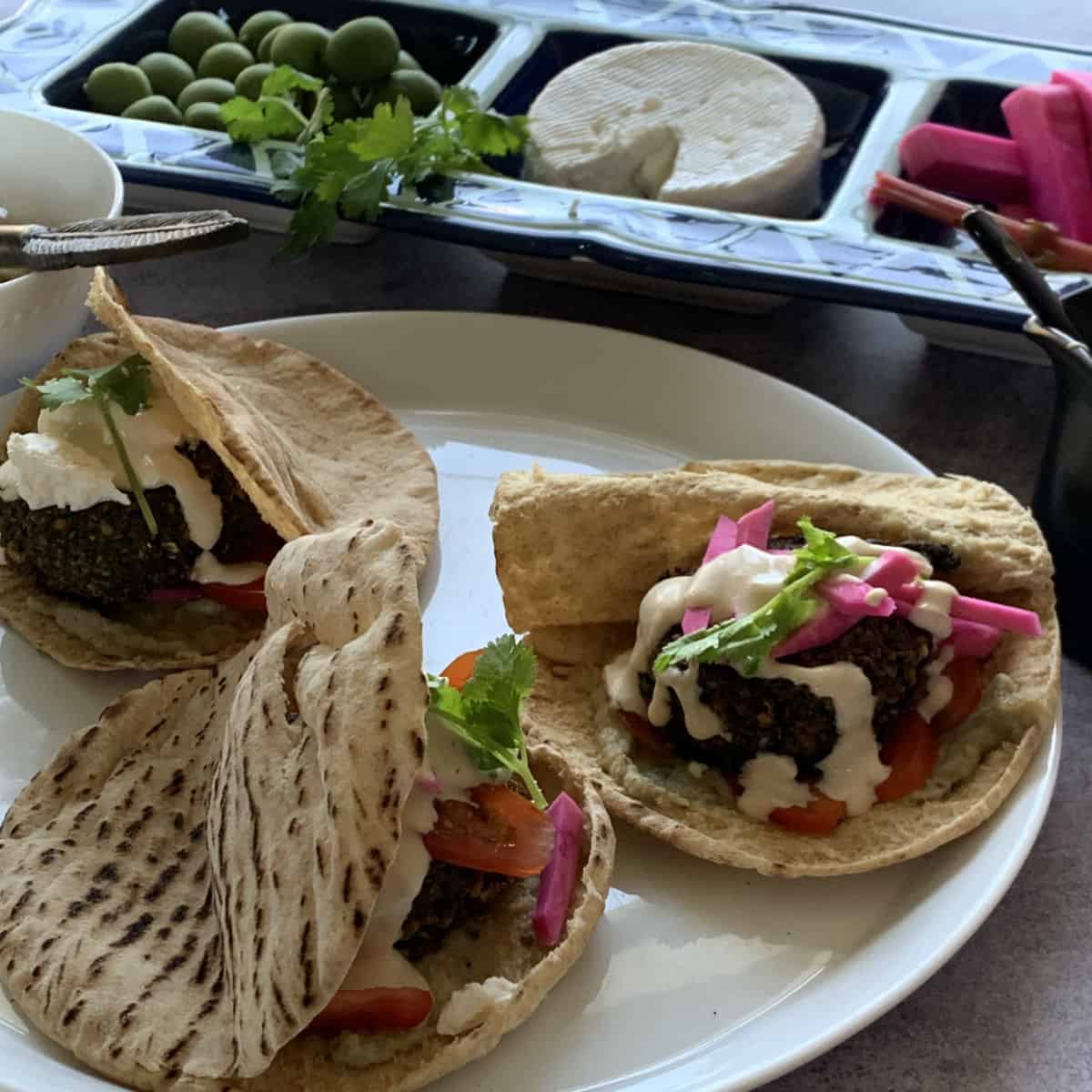 Assembling Falafel patties on a pita bread.