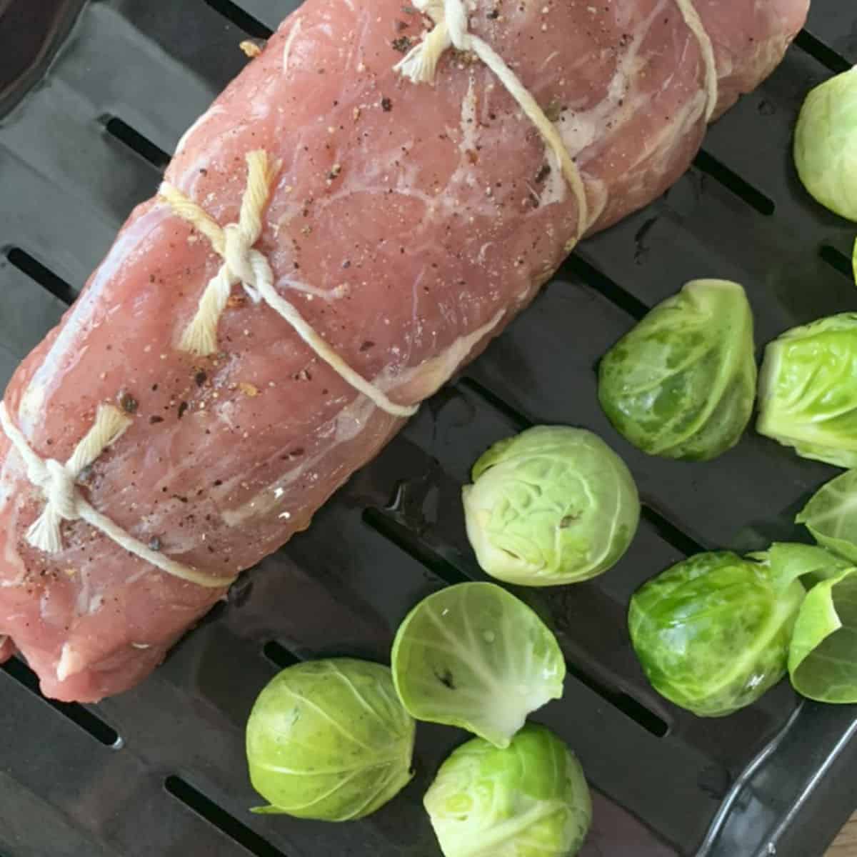 Pork tenderloin on with Brussel sprouts a roasting pan.