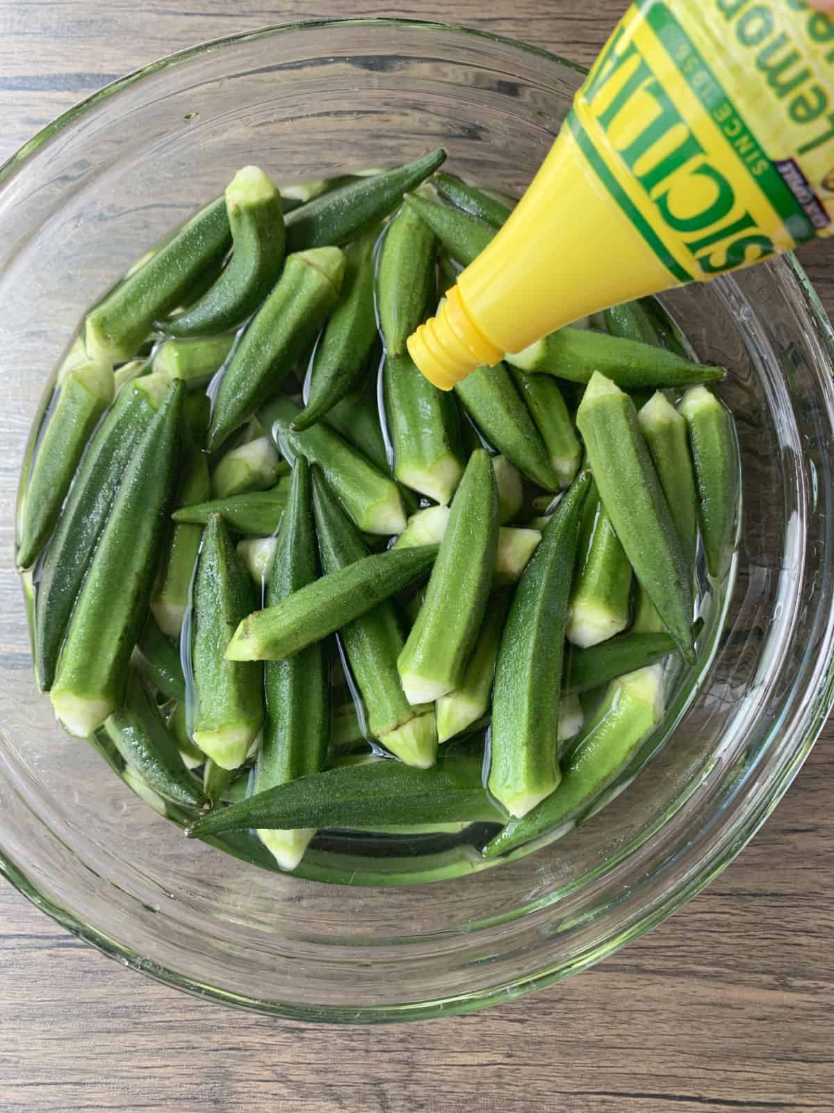 Trimmed okra in a water lemon bath.