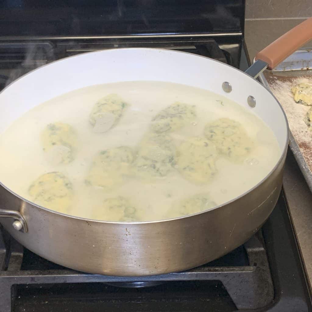 Gently cooking the gnudi in simmering water.