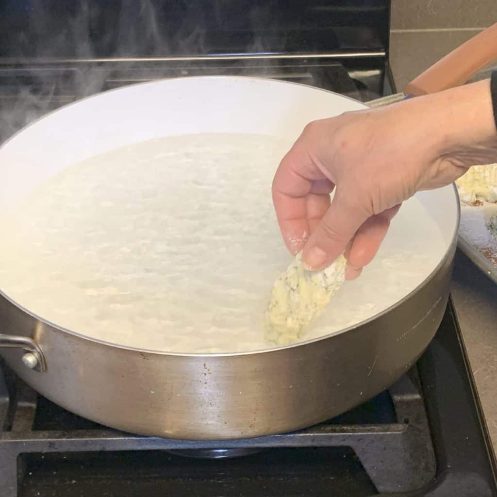 Adding the pre-made ricotta gnudi to the boiling water.