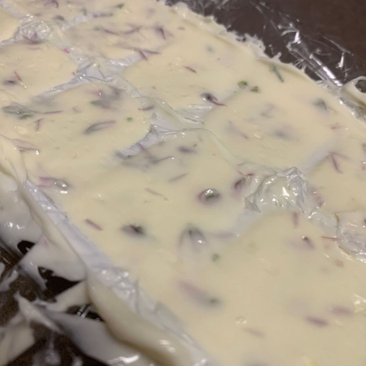 Chive blossom compound butter in an ice cube tray.