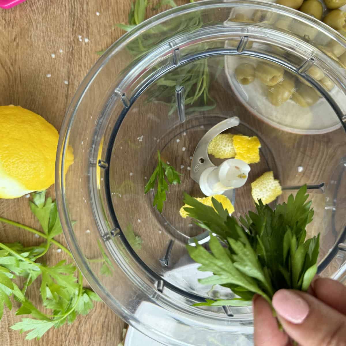 Adding parsley and tarragon into food processor.