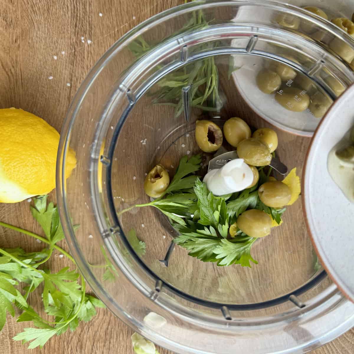 Adding olives and capers into food processor.
