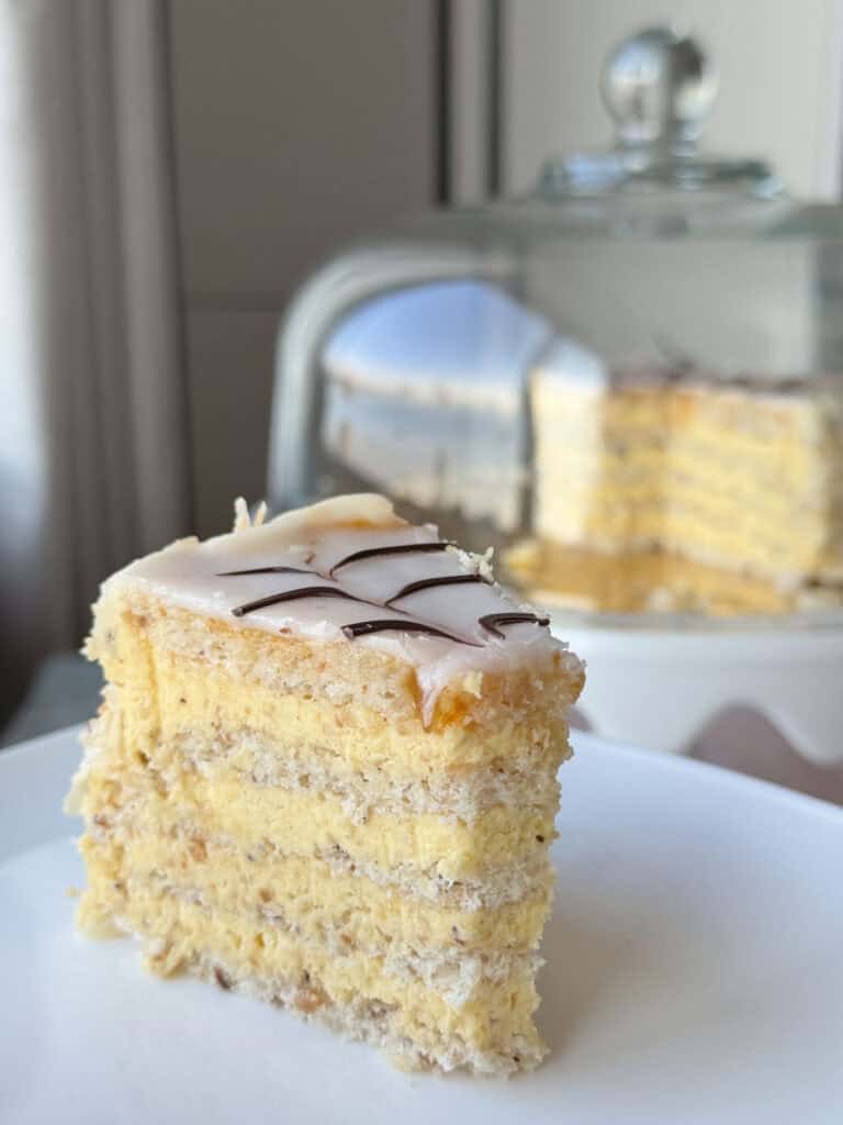 A slice of Esterházy Torte and a cloche on the background.