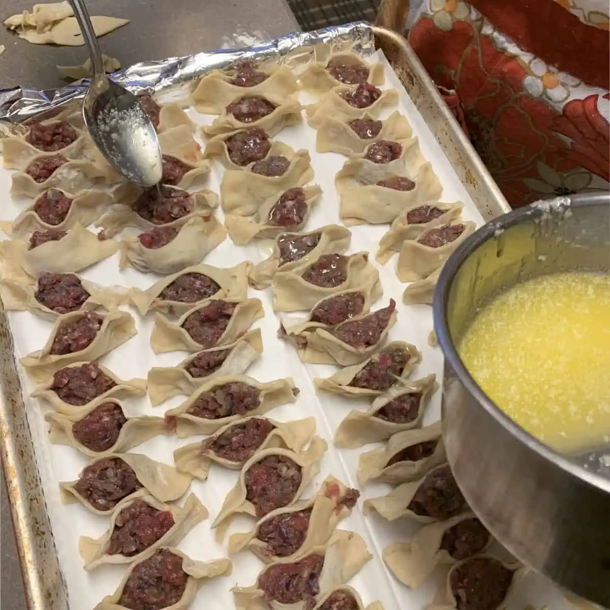 Drizzling the melted butter on the ready boats.