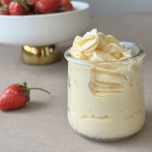 A Mousseline Cream in a jar and a bowl of strawberries.