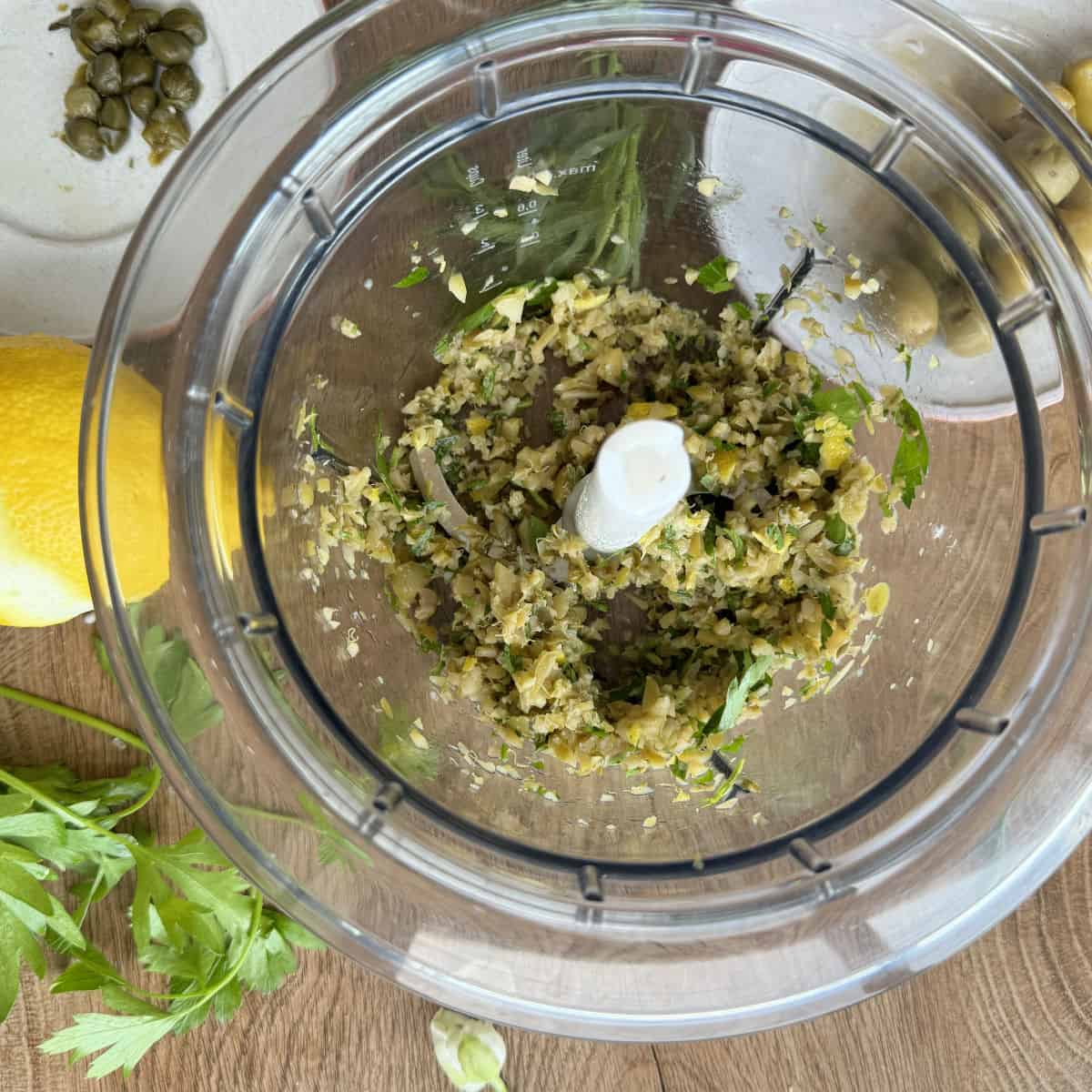 Adding olives and capers into food processor.