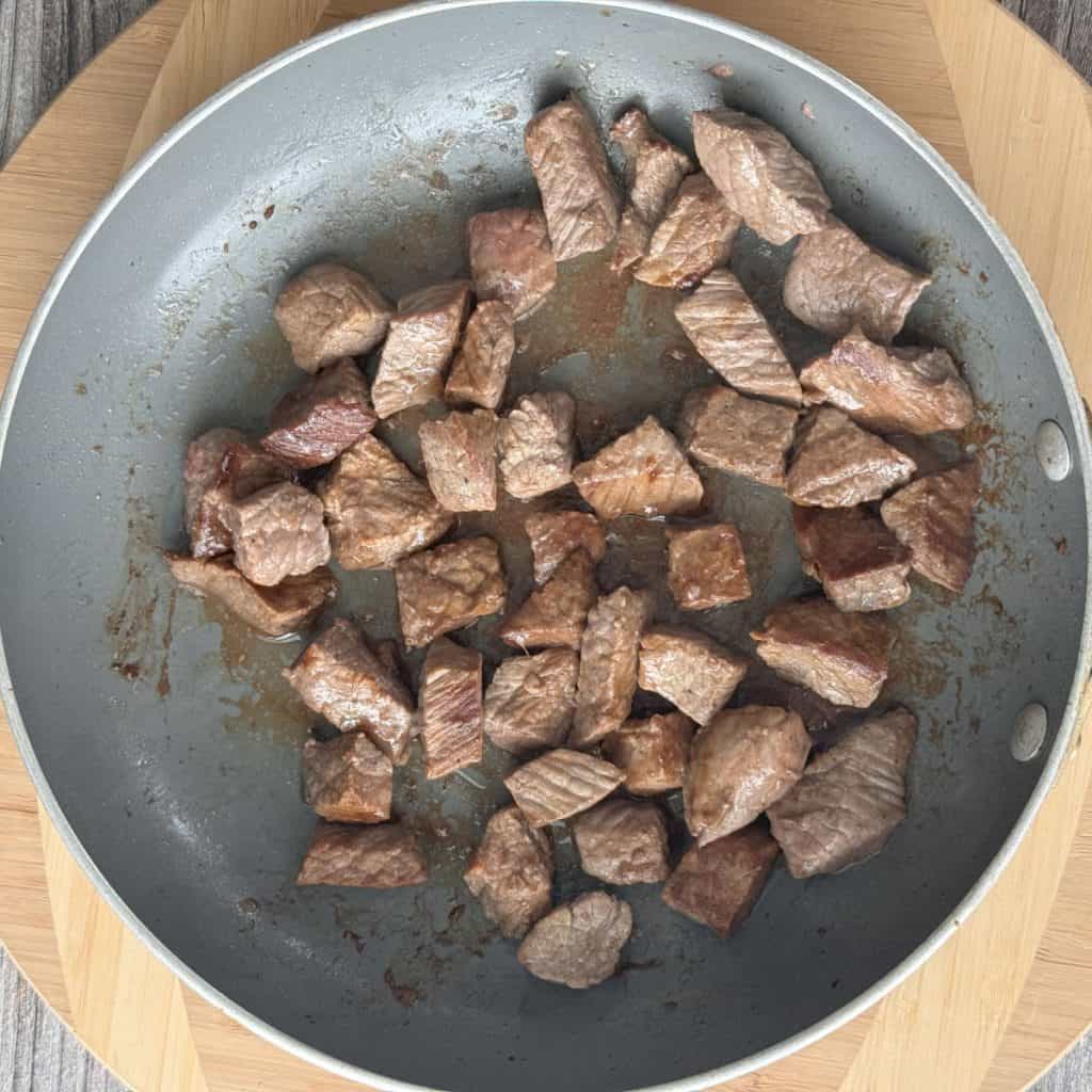 Browned stew meat in a frying pan.