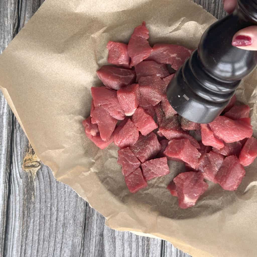 Seasoning stew meat with pepper.