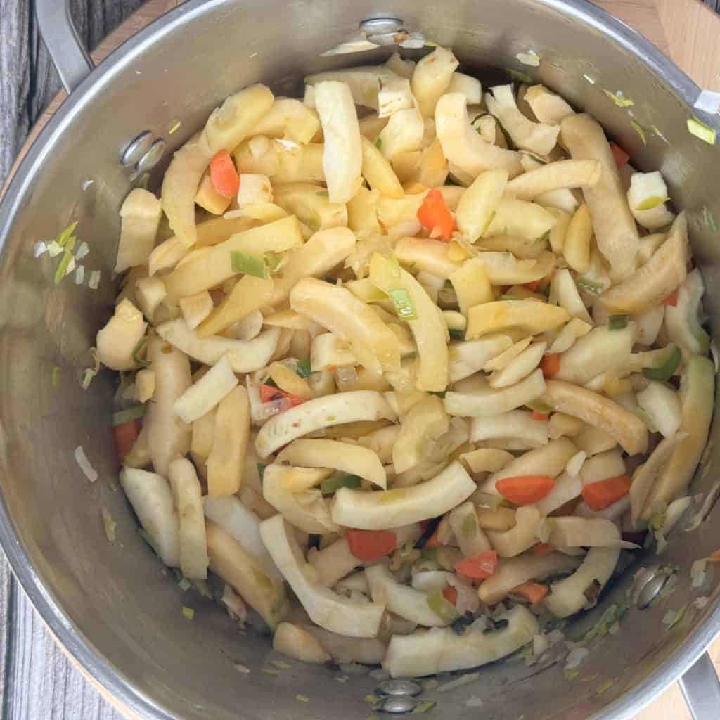 Sautéing the chopped vegetables in a pot.