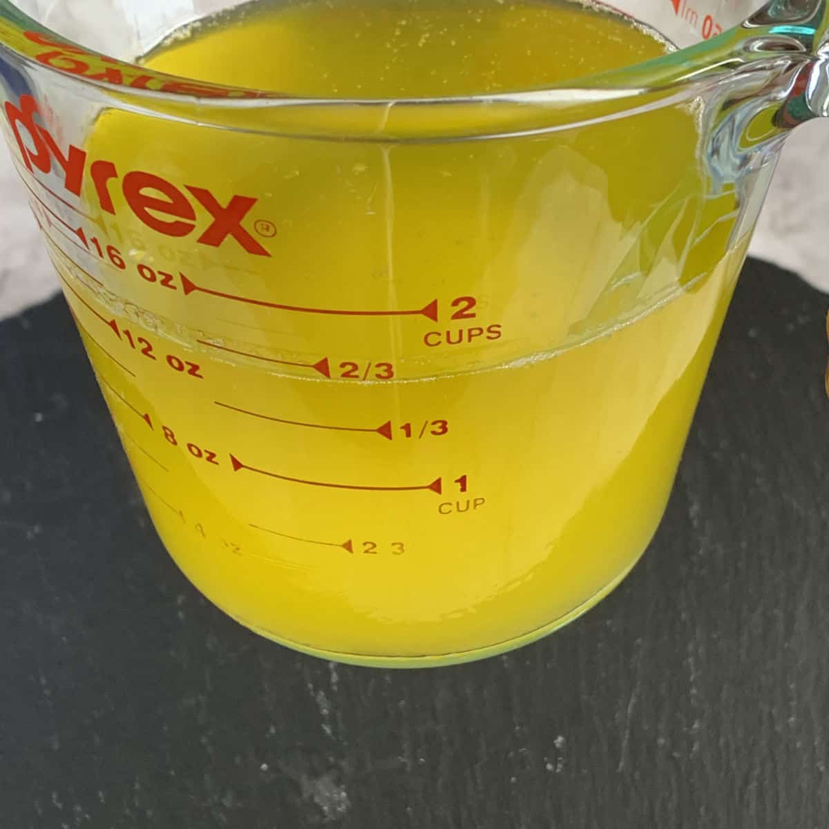 Melted butter, ghee in a glass measuring cup.
