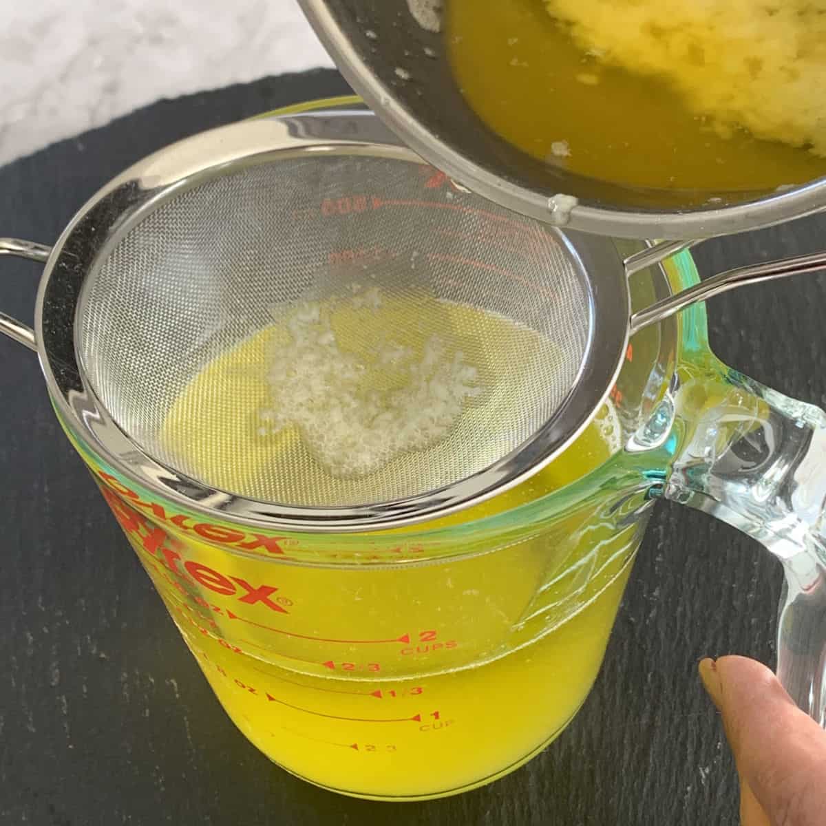 Straining the melted butter through a sieve.