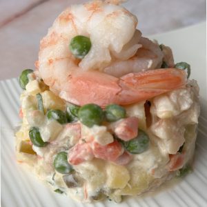 A plate of olivier salad with shrimp and vegetables.