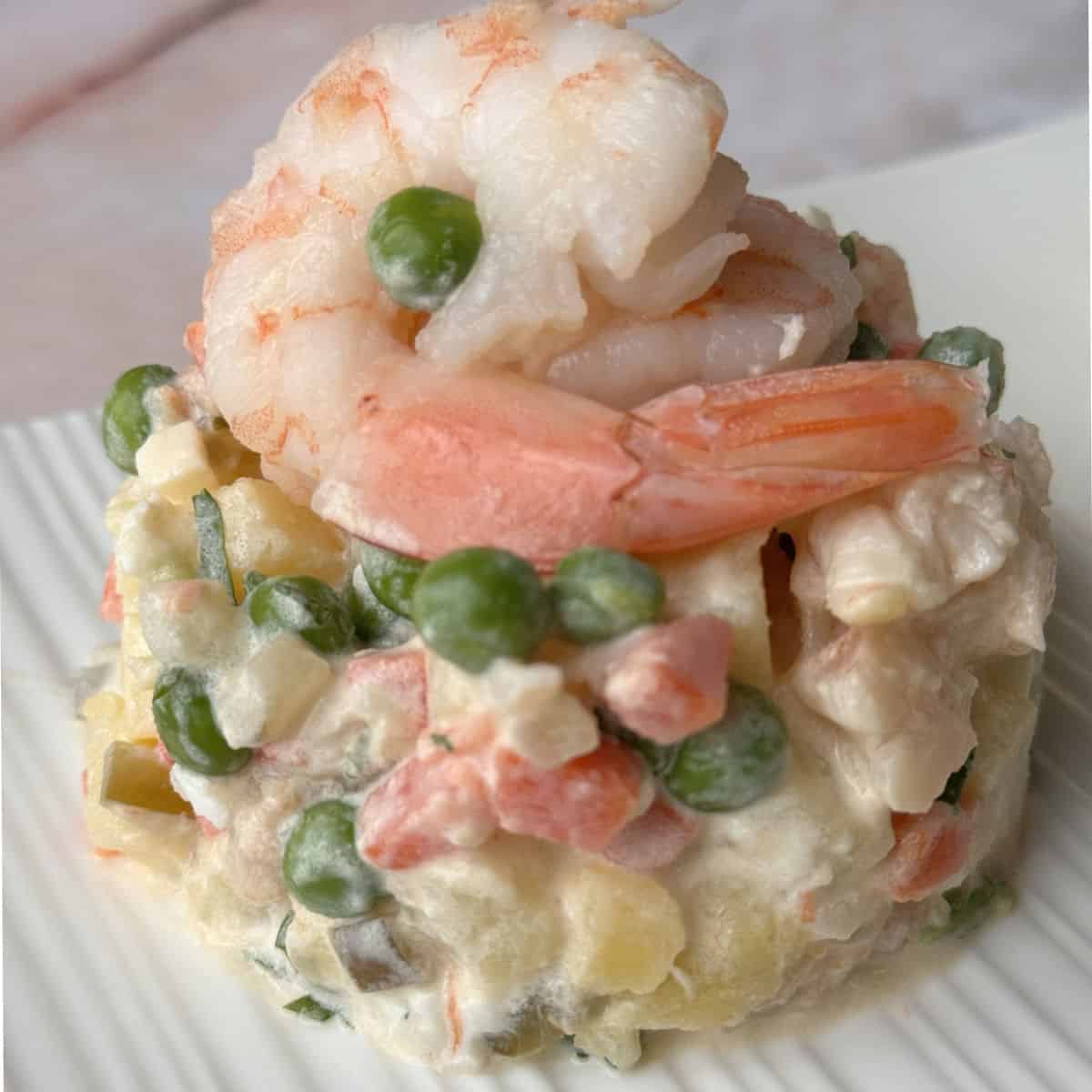 A plate of olivier salad with shrimp and vegetables.
