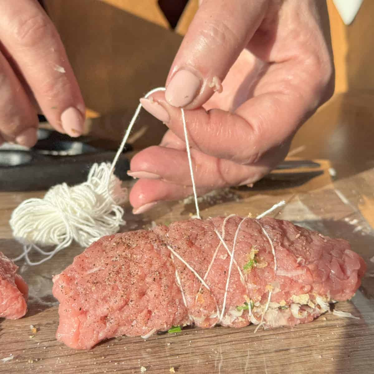 Process shots of making braciole, wrapping with the string.