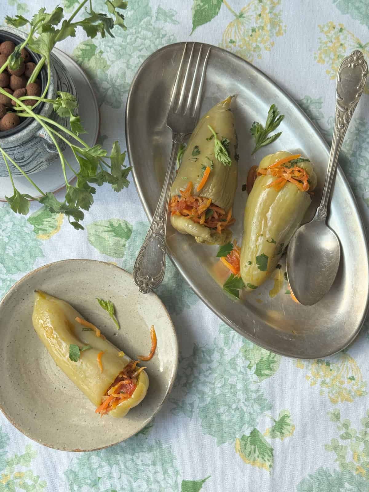 Stuffed pepper on a metal dish with spoon and fork for serving.