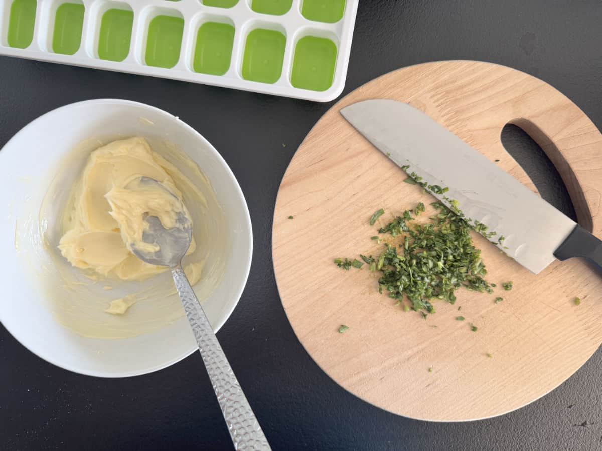 Chopped tarragon on the cutting board and a soften butter.