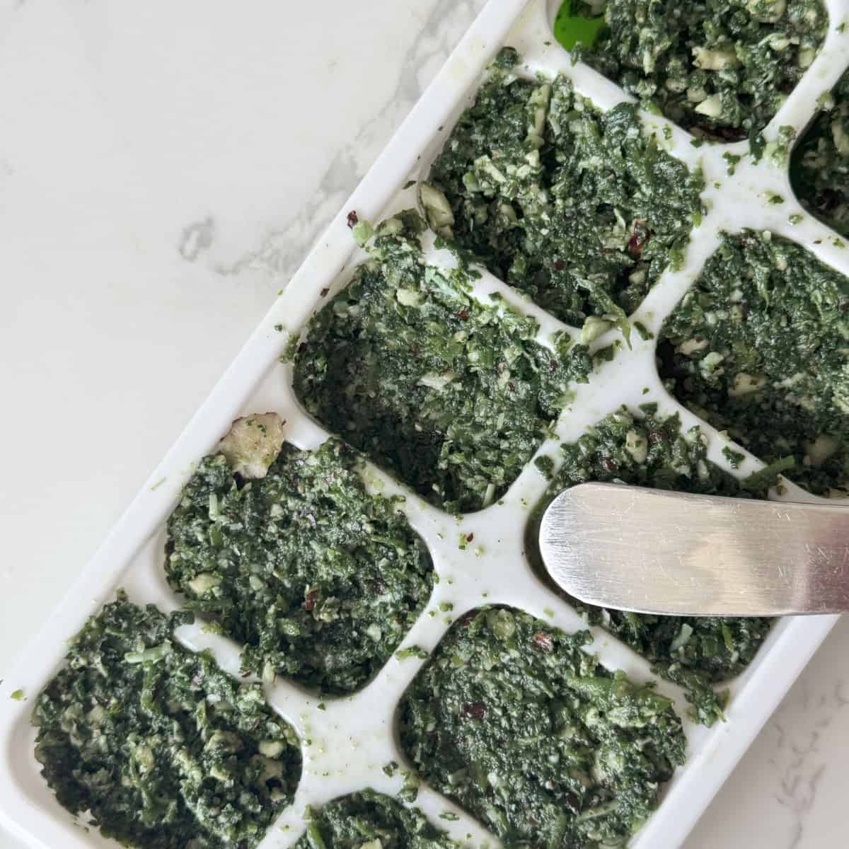 Spreading nettle pesto into ice cube tray.