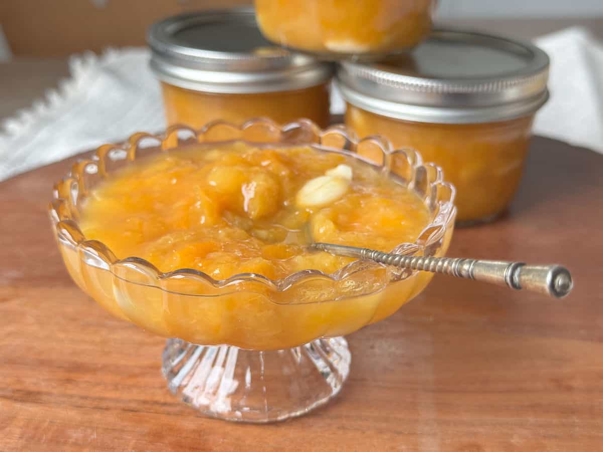 Apricot jam in a vase and a coupe of jars in the background.