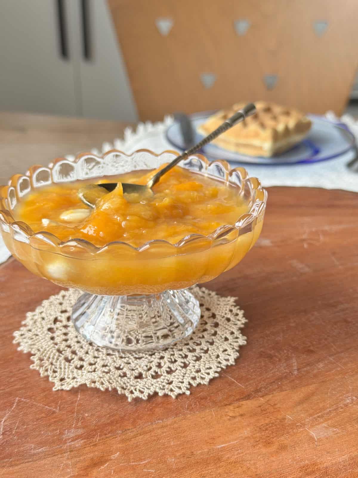 Apricot jam in a vase with the waffle in the background.