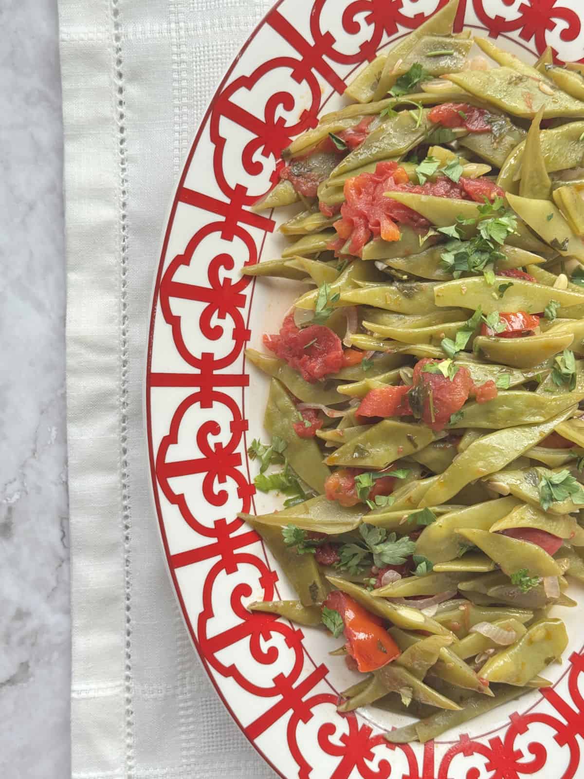 A bird’s-eye view of a dish with green beans and tomatoes.
