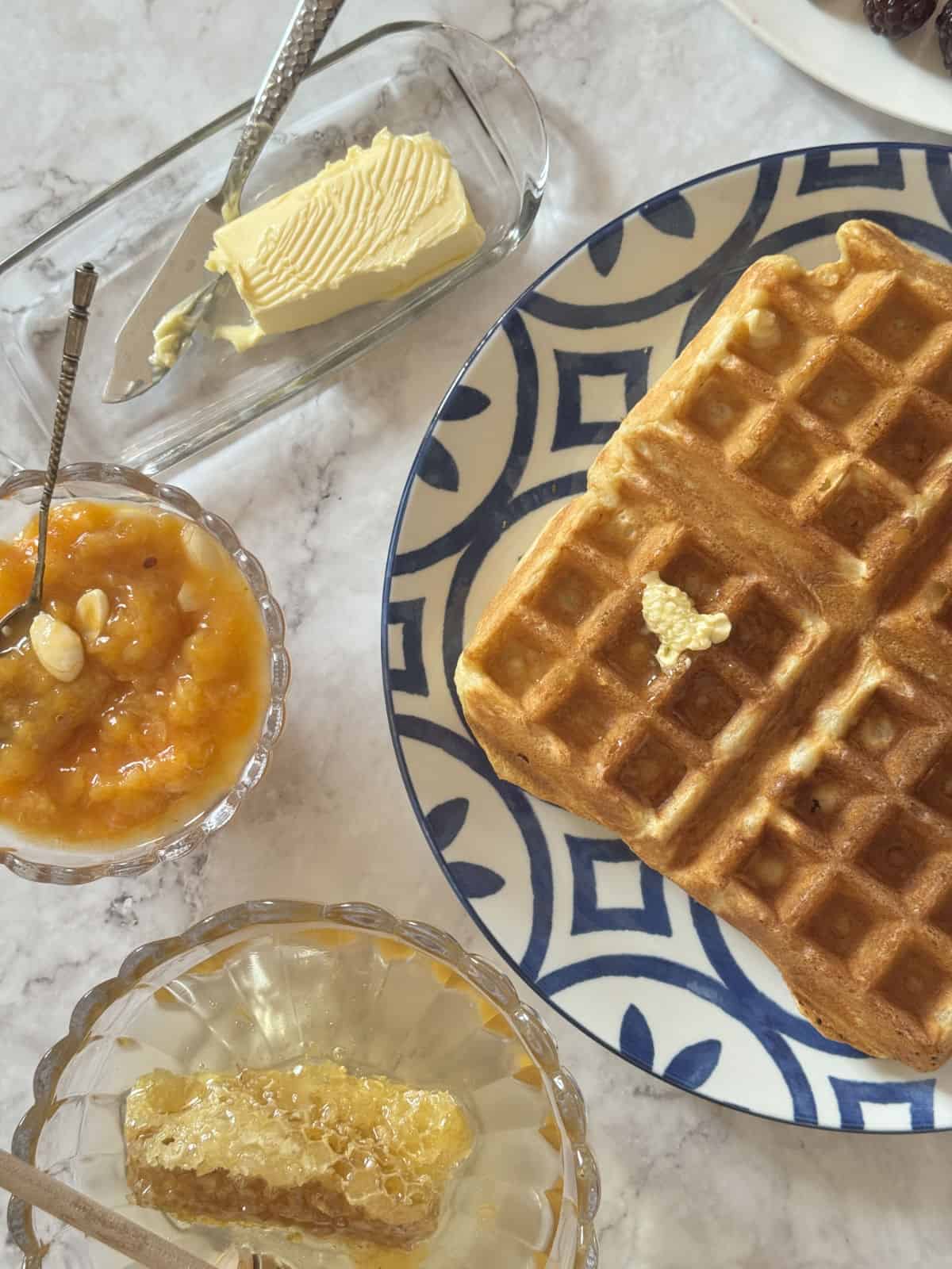 Overhead shot of the kefir waffle with a butter, apricot jam and honey comb.