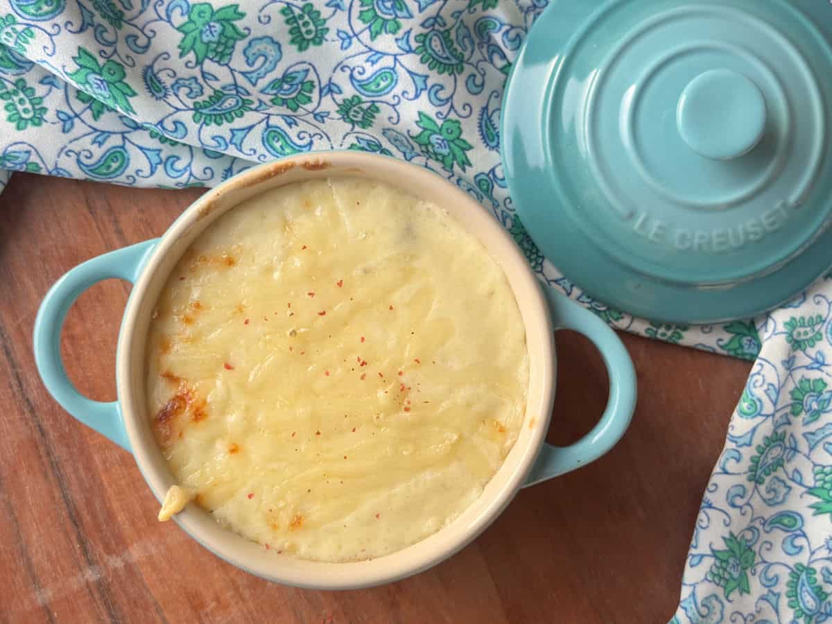 An overhead shot of a chicken julienne in a turquoise blue ramekin dish name arranged on a wooden table.