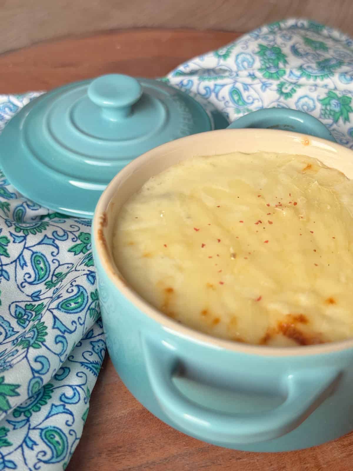 A close-up of a chicken julienne in a turquoise blue ramekin dish name arranged on a wooden table.