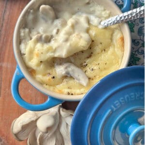 A spoon scooping a portion of mushroom julienne in a blue ramekin revealing its creamy, rich texture.