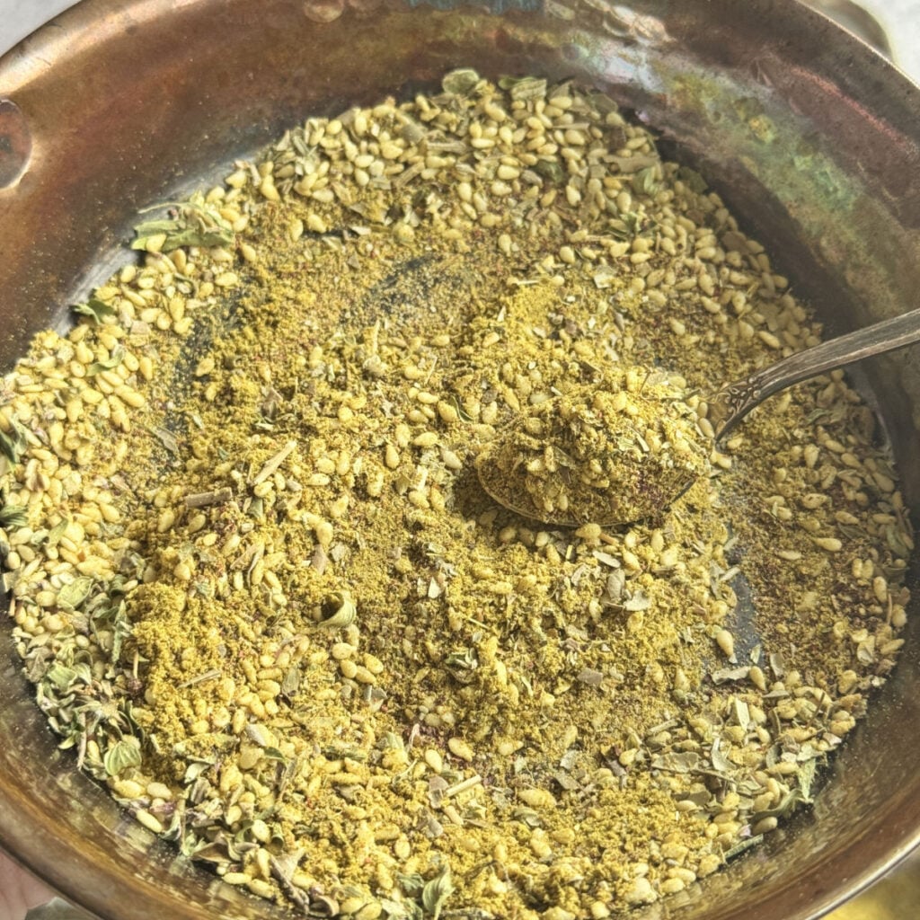 Za'atar spice blend being mixed in a hot skillet, oregano, thyme, and sumac combined.