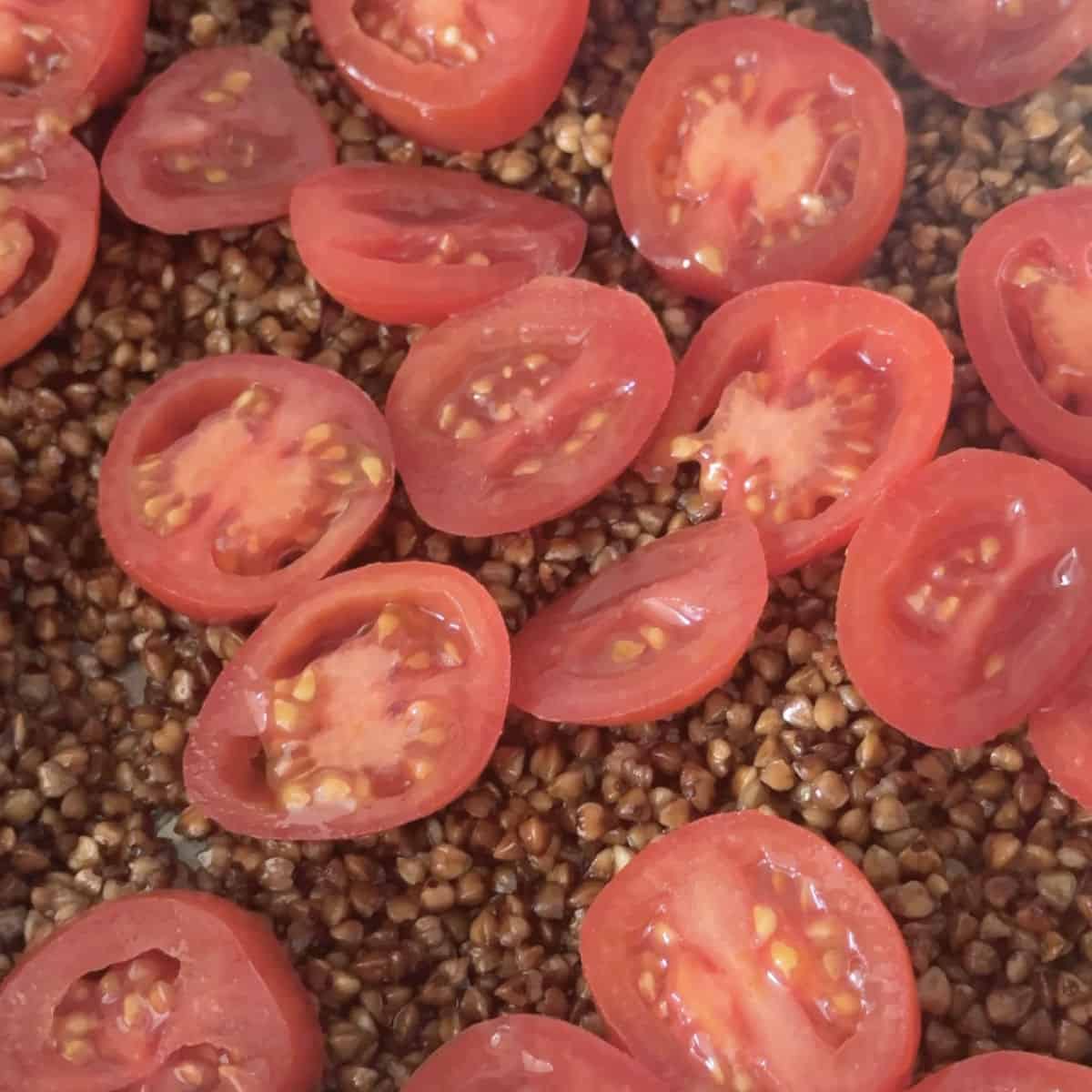 Placing sliced tomatoes on top of toasted buckwheat.