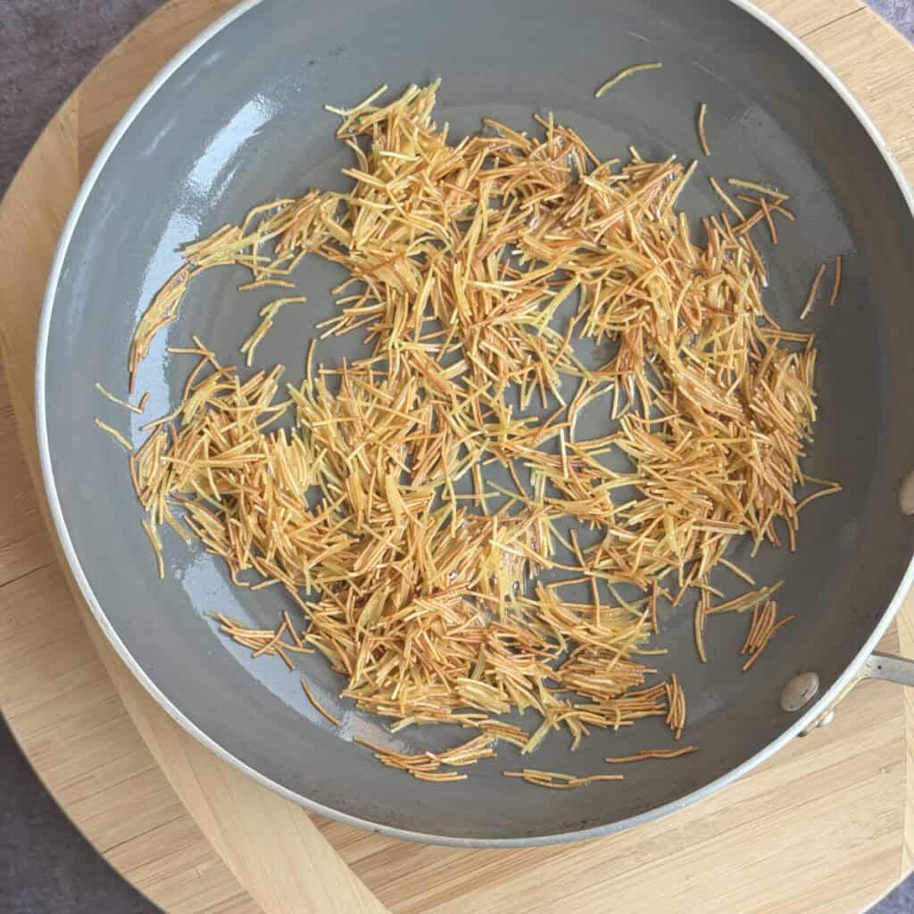 Broken vermicelli toasting in butter to a deep golden brown.
