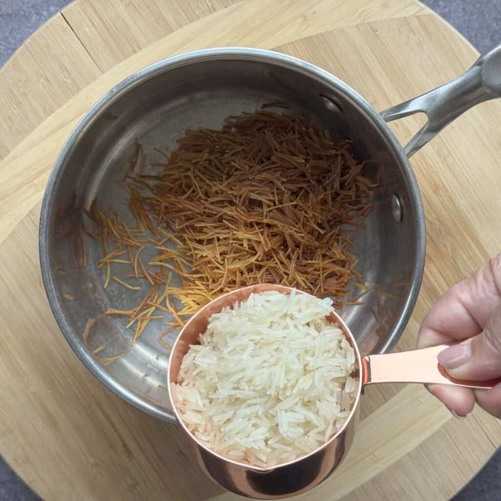 White rice stirred into golden toasted vermicelli in the saucepan.